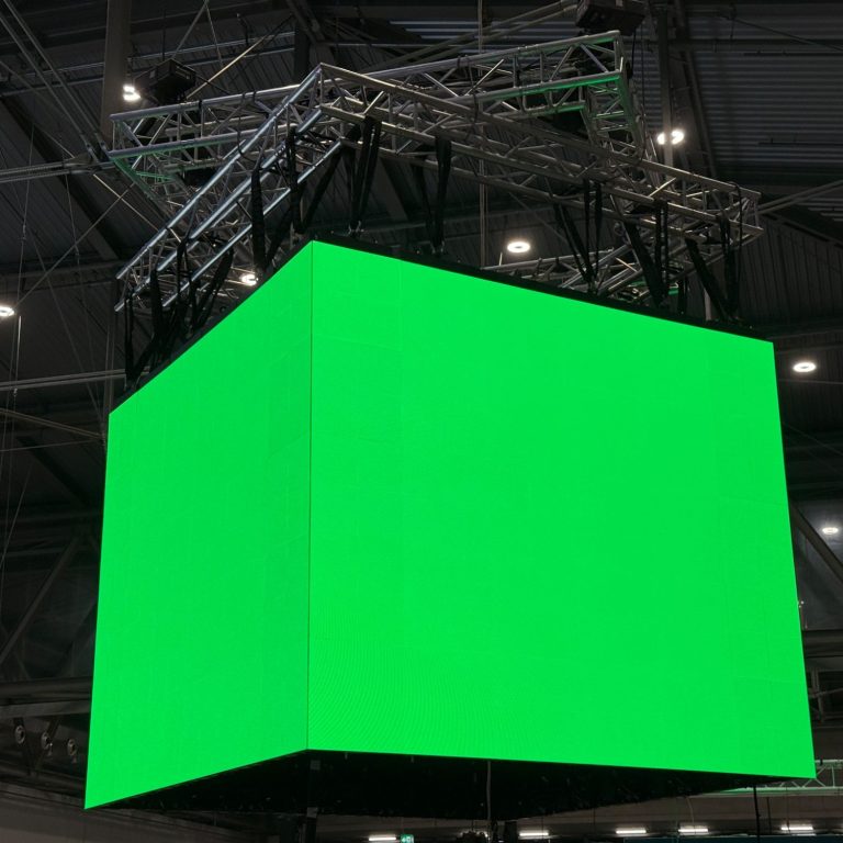 LED-Cube Installation für Messe- und Veranstaltungstechnik Grüner, leuchtender LED-Bildschirm hängt über einer Veranstaltungshalle.