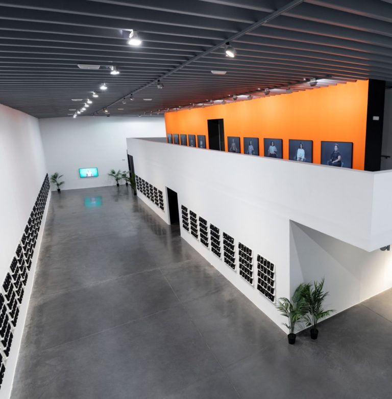 Techniker bei der Installation einer großformatigen LED-Displaystruktur auf einer Messe Techniker zeigt auf große, komplexe Bühne mit vielen schwarzen Panels im Hintergrund.