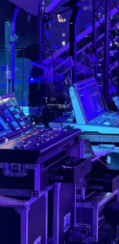 RGpro | Technische Lösungen für Tech-Pros Blick auf einen Technik-Pult mit blauen und lila Lichtern im Hintergrund.