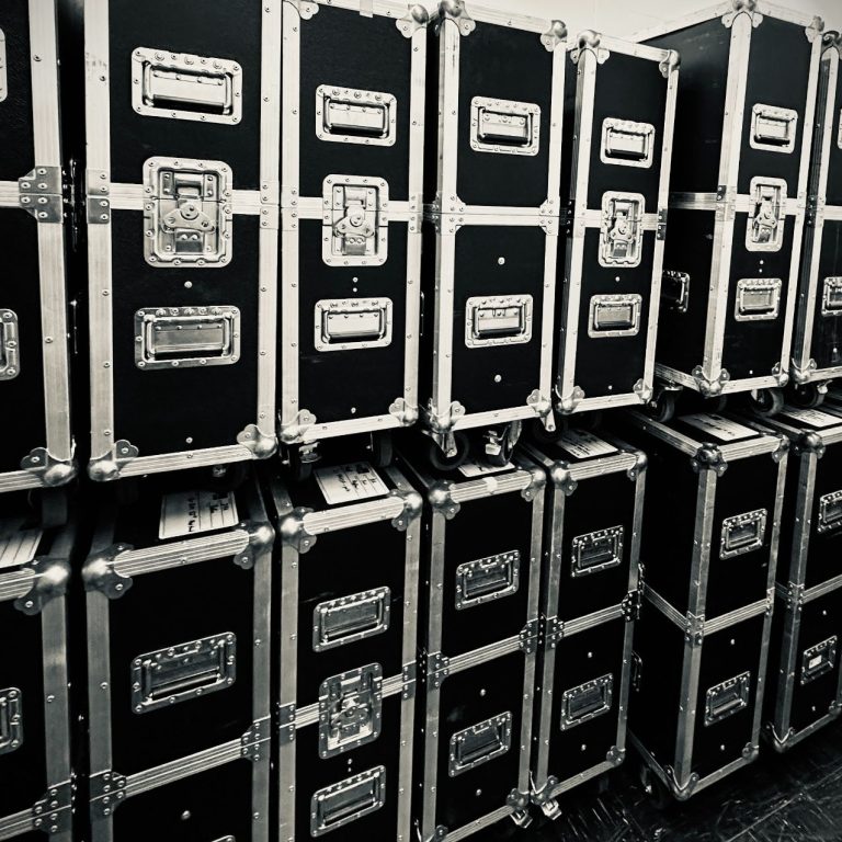 Flightcases für Video- und Veranstaltungstechnik Schwarze Transportkisten in gestapelter Formation mit silbernen Beschlägen.